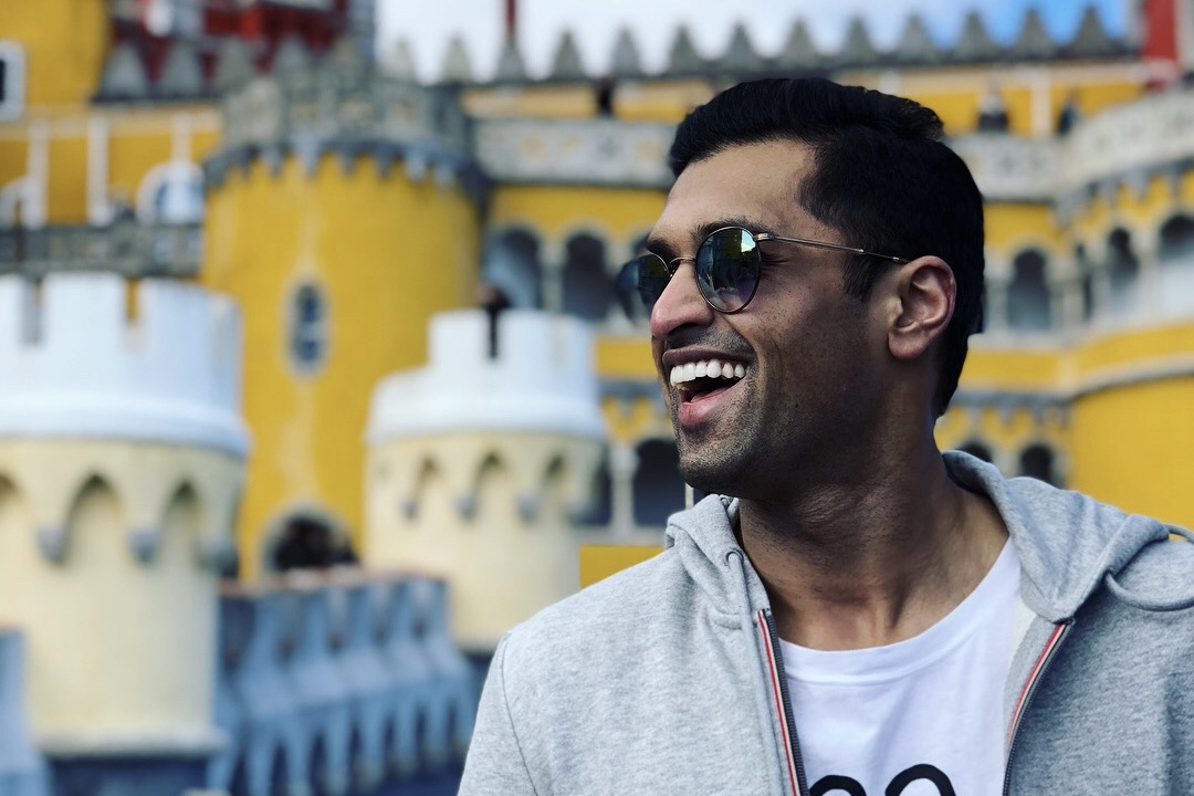 a man smiling in front of a colourful building 