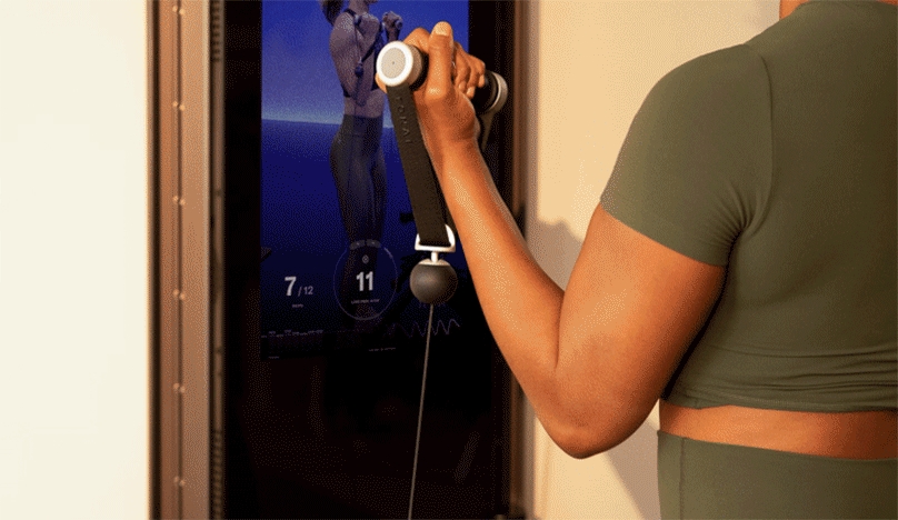 Close up of a woman using Tonal handles to complete a Bicep Curl.